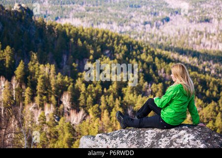 Jeune femme assise sur le bord de la falaise. Banque D'Images