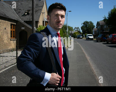 Handsome businessman aux yeux bleus et à l'uniforme dans la rue croix ville rurale Banque D'Images