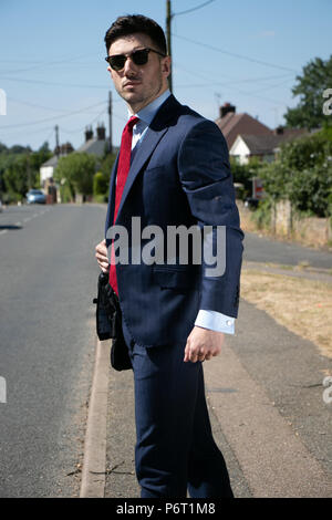 Handsome businessman aux yeux bleus et à l'uniforme dans la rue croix ville rurale Banque D'Images