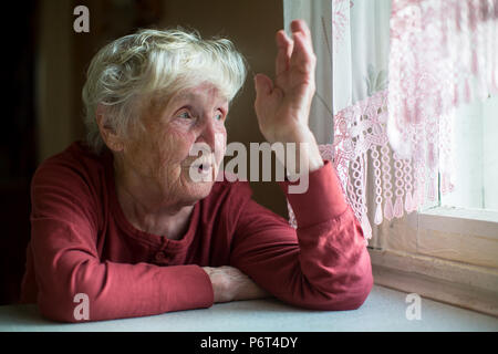 Vieille Femme Russe émotionnellement parlant assis à une table à la maison. Banque D'Images