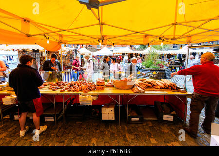 Vue de derrière du pain français avec blocage des pains et baguettes françaises sur les personnes à la recherche et l'achat avec. Toile de fond d'autres étals du marché couvert. Banque D'Images