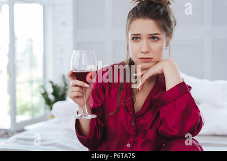 Femme aux yeux verts en pyjama rouge sombre sentiment terrible Banque D'Images