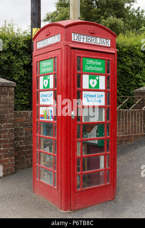 L'utilisation nouvelle et originale pour les vieux téléphone rouge britannique fort abritant un défibrillateur et échange de livres d'occasion Banque D'Images