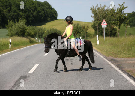 Oberoderwitz, jeune fille traverser un chemin de campagne sur son poney Shetland Banque D'Images