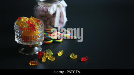 Marmelade dans un vase sur la table. Bonbons dans un bol sur un fond noir. Jelly multicolore des bonbons pour les enfants. Banque D'Images