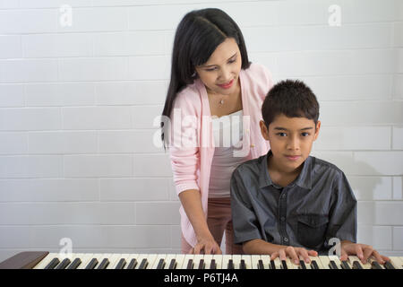 Garçon avec le professeur de musique ayant cours à Piano Banque D'Images