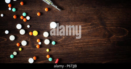 Médicaments et pilules sur une table en bois. Divers moyens pour prévenir les rhumes. Thé au citron et de miel. Tasse en verre avec plateau tranche de citron et un pot de miel. Banque D'Images