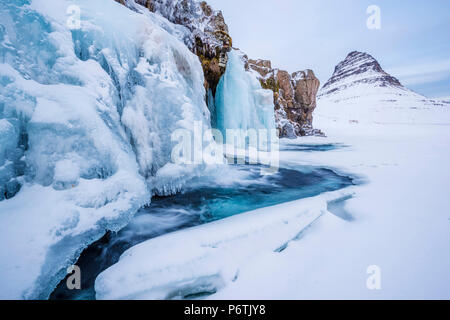 La péninsule de Snaefellsness, dans l'ouest de l'Islande, l'Europe. Chute d'Kirkjufellfoss congelés en hiver avec Kirkjufell mountain dans la toile. Banque D'Images
