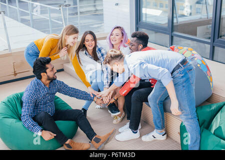 Groupe de jeunes designers jouful multiethnique mâle et femelle donner cinq après la signature d'un contrat avec les partenaires à l'étranger sur le bureau en plein air d'une terrasse. Banque D'Images