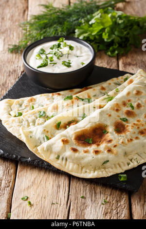 La nourriture végétarienne simple : le pain plat qutab avec les verts et le yogourt close-up sur la table. Une cuisine azerbaïdjanaise. vertical Banque D'Images