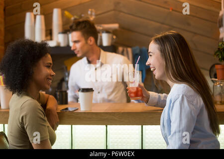 Copines multiraciale de rire, prendre un verre au bar Banque D'Images