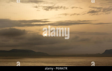 Un beau jaune smokey lever ou le coucher du soleil avec des îles au loin et les nuages dans le ciel Banque D'Images