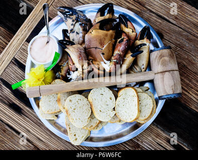 Plate avec des pattes et pinces de crabe brun avec du pain et le tremper sur table en bois Banque D'Images