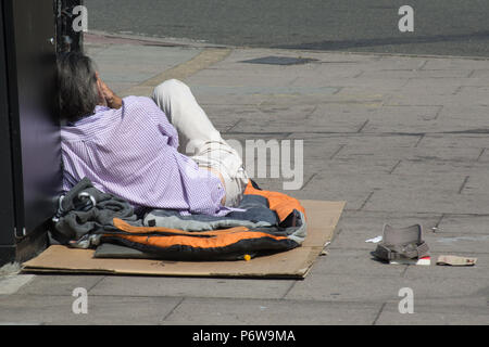 Homme sans domicile sur le trottoir devant la gare de Guildford, dans le Surrey, UK Banque D'Images