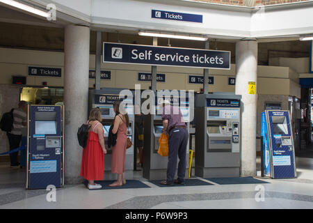 Les passagers l'achat de billets de train à partir de machines en libre service à l'intérieur de la billetterie à la gare de Guildford, Surrey, UK Banque D'Images