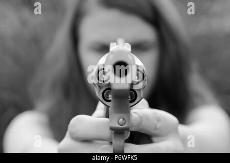 Une fille visant un revolver chargé avec des balles à pointe creuse tourné en noir et blanc Banque D'Images