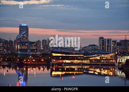 Vue de la ville de Londres, Canary Wharf, la ligne d'Horizon Air sky tram, et de l'O2 Arena se reflétant dans l'eau du Royal Victoria Dock au coucher du soleil Banque D'Images