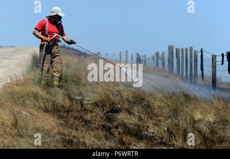 Bolton, Lancashire, UK. 2 juillet, 2018. Les pompiers de Lancashire et autres forces continuent de s'attaquer à un énorme incendie landes sur la colline d'hiver près de Bolton, Lancashire. Le brasier a été commencé et délibérément fait rage pendant six jours couvrant une superficie de 7 kilomètres carrés. Les pompiers de la Lancaster inscrivez-vous dans l'effort à l'aide de tiges de pénétration du sol pour combattre le feu au-dessous du sol. Banque D'Images