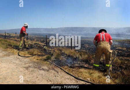 Bolton, Lancashire, UK. 2 juillet, 2018. Les pompiers de Lancashire et autres forces continuent de s'attaquer à un énorme incendie landes sur la colline d'hiver près de Bolton, Lancashire. Le brasier a été commencé et délibérément fait rage pendant six jours couvrant une superficie de 7 kilomètres carrés. Les pompiers de la Lancaster inscrivez-vous dans l'effort à l'aide de tiges de pénétration du sol pour combattre le feu au-dessous du sol. Banque D'Images