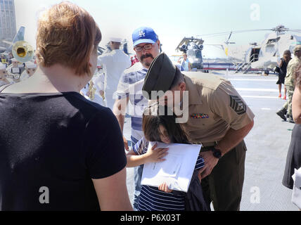 San Diego, CA, USA. 3 juillet, 2018. Le sergent d'artillerie marine. Rafael Dominguez Garcia embrasse sa fille Emma Juliette DominguezÃ¢â€ tête alors qu'elle a tenu ses travaux à la suite d'un papier de la citoyenneté cérémonie sur le pont de l'USS Midway Museum. Dominguez Garcia est d'origine mexicaine, né et élevé à Mexicali. L'une la veille du 242e anniversaire de l'Organisation des États lorsque le Congrès continental a adopté la Déclaration d'indépendance, marins, soldats, marins et coastguardsmen ont prêté serment en tant que citoyens des Etats-Unis lors d'une cérémonie à bord du USS Midway Museum. (Crédit Image : © John G Banque D'Images