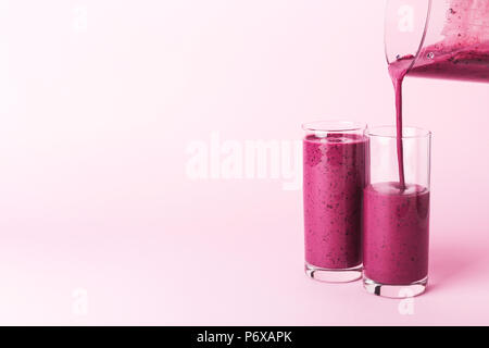 Deux verres de smoothie aux bleuets sur fond rose. Penché de Blender en verre. Banque D'Images