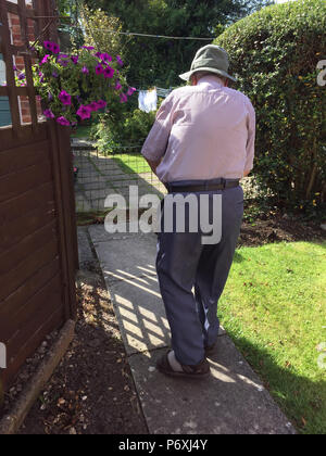 Vue arrière du vieil homme marchant dans chemin de jardin Banque D'Images