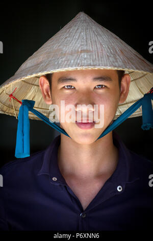 Portrait de jeune homme au chapeau conique traditionnel à Can Tho, Vietnam Banque D'Images