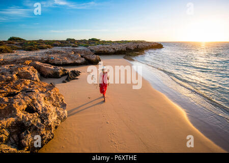 Osprey Bay, Cape Range National Park, Exmouth, Australie occidentale, Australie. Femme élégante robe rouge avec chapeau de paille et d'admirer le sunsset (MR). Banque D'Images