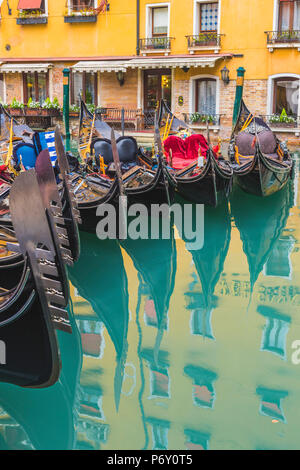 Venise, Vénétie, Italie. Les gondoles amarrées coloré reflétant dans l'eau. Banque D'Images