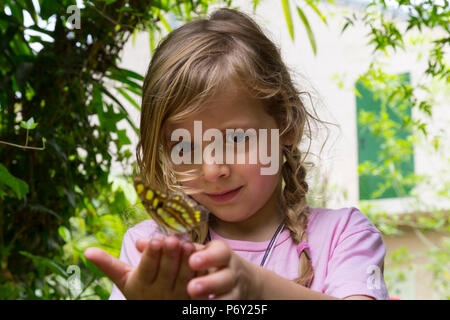 Fille avec un papillon reposant sur ses doigts. Low angle view. Medium close-up. Banque D'Images