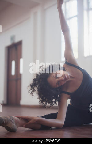 Jeune danseuse gracieuse qui s'étend dans un studio de danse Banque D'Images