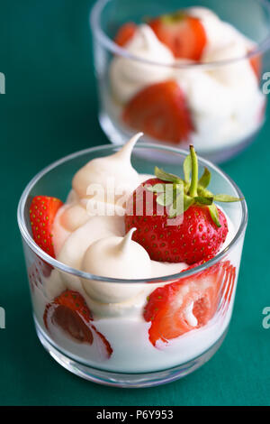 Wimbledon inspiré de la crème fouettée, des meringues et de fraises fraîches dans un bol en verre sur fond vert. Banque D'Images