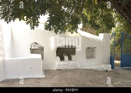 La Cour d'une maison traditionnelle grecque à Kalymnos, Grèce. Cuisine extérieure avec zone d'origine caroubier en surplomb. Banque D'Images