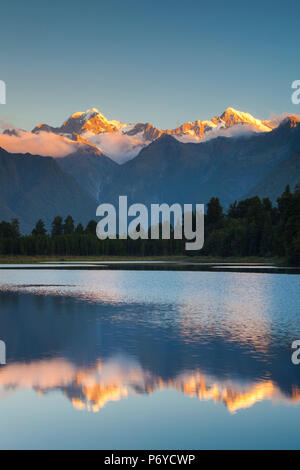 Nouvelle Zélande, île du Sud, Côte Ouest, Fox Glacier Village, Lake Matheson, reflet de Mt. Tasman et Mt. Cook, crépuscule Banque D'Images