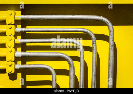 Cinq tuyaux en métal incliné en avant du mur d'acier de couleur jaune vif Banque D'Images