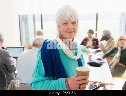 Portrait confiant senior businesswoman drinking coffee in meeting Banque D'Images