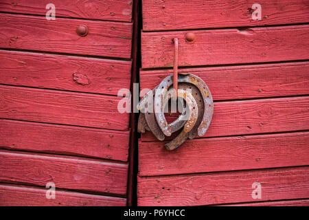 Old rusty fers accroché sur la poignée de porte en bois rouge Banque D'Images