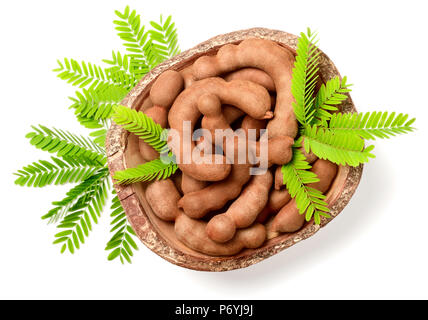 Tamarin frais les fruits et les feuilles dans le bol en bois, isolé sur le fond blanc, vue du dessus Banque D'Images