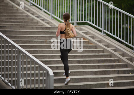 Mettre en place jolie fille courir vers le haut des escaliers avec arrière-plan de la ville Banque D'Images