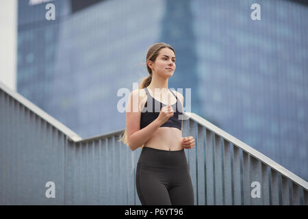 Mettre en place jolie fille courir vers le haut des escaliers avec arrière-plan de la ville Banque D'Images