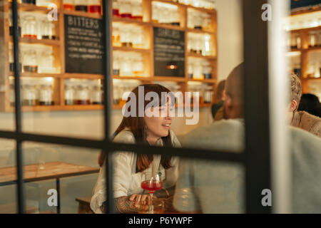 Jeune femme parlant avec des amis autour d'un verre dans un bar Banque D'Images