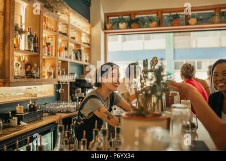 Smiling female bartender discuter avec les clients à un comptoir bar Banque D'Images