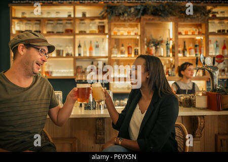 Deux smiling young friends cheering avec boissons dans un bar Banque D'Images