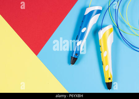 Stylos 3d avec des filaments de plastique en couleur sur fond bleu, vue d'en haut Banque D'Images