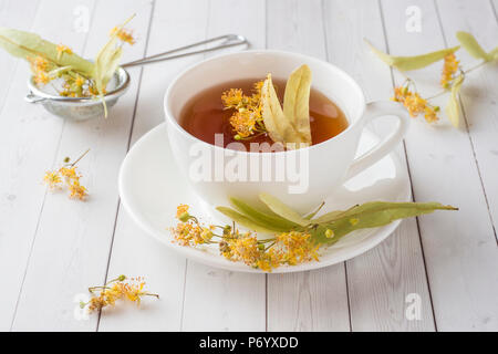 Tasse de thé avec des fleurs de tilleul sur une table lumineuse. Banque D'Images
