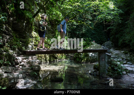 Les promeneurs aventureux négocier dans le terrain modéré près de la gorge rocheuse 15m de haut Kozjak Cascades, une partie de la piste du patrimoine de Kobarid, le 21 juin 2018, à Kobarid, Slovénie. Banque D'Images