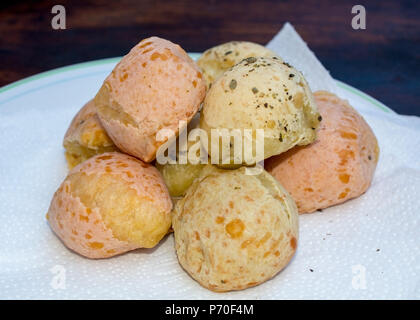 Gros plan sur la bouche-arrosage brésilien chevronné (pain au fromage Pao de Queijo") a servi de serviette blanc sur blanc et la plaque de fond de table en bois brésilien- cu Banque D'Images