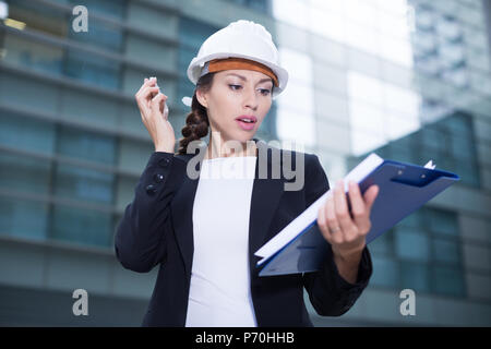 Femme designer en costume et chapeau est en dossier et discuter de projet par le téléphone près de l'immeuble. Banque D'Images