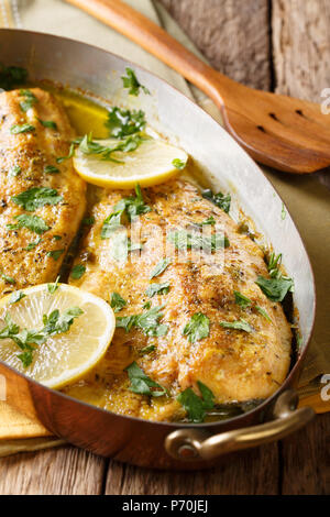 Filets de truite au four épicées avec sauce au beurre à l'ail, le citron et le persil close-up dans une poêle de cuivre sur une table verticale. Banque D'Images