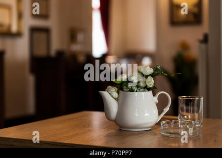 Restaurant intérieur avec Décoration Pot à lait en céramique avec des fleurs sur une table en bois avec une galerie à l'arrière-plan Banque D'Images